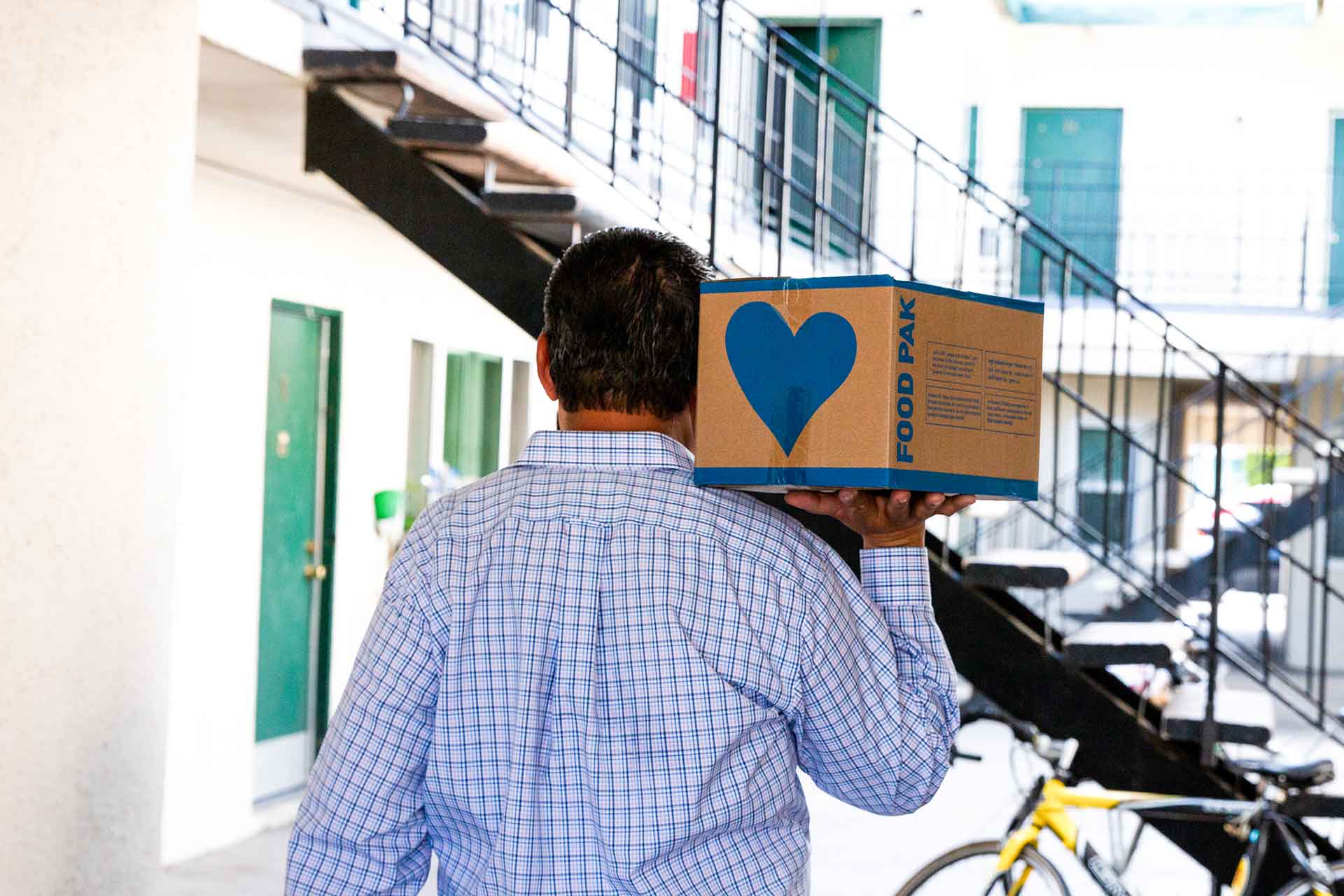 A local pastor hands a Food Pak to a family at their door